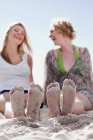 Primer plano de los pies arenosos de las mujeres en la playa - foto de stock