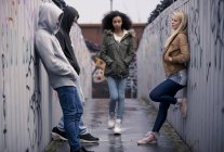 Adolescentes de pie contra la pared con graffiti - foto de stock