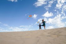 Mãe e filho voando pipa na praia — Fotografia de Stock