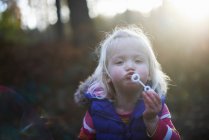 Menina da criança soprando bolhas no parque outonal em backlit — Fotografia de Stock
