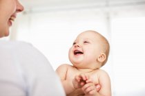 Mother holding laughing baby girl — Stock Photo