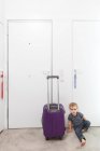 Boy by rolling luggage in hallway — Stock Photo