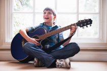 Хлопчик грає на гітарі на підлозі — стокове фото