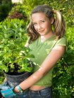 Sorridente ragazza che tiene pianta in vaso — Foto stock