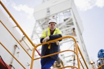 Trabalhador inclinado sobre trilhos de equipamento de petróleo — Fotografia de Stock