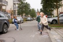 Enfants jouant dans la rue de banlieue — Photo de stock