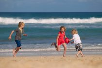 Enfants jouant avec la balle rouge sur la plage — Photo de stock