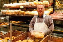 Улыбающийся пекарь держит буханку хлеба — стоковое фото