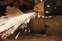 Sparks from worker using grinder in factory — Stock Photo