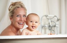 Smiling mother bathing with baby, focus on foreground — Stock Photo