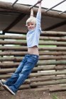 Rapaz balançando de barras de macaco, foco seletivo — Fotografia de Stock