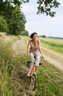 Жінка їде на велосипеді по сільській дорозі — стокове фото