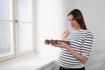 Donna incinta in possesso di biscotti al cioccolato — Foto stock