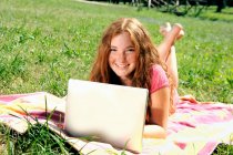 Mädchen benutzt Laptop auf Gras — Stockfoto
