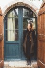Ritratto di giovane donna che alza lo sguardo dalla porta di casa — Foto stock