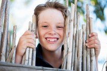 Boy smiling behind fence, focus on foreground — Stock Photo