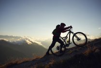 Горный байкер, толкающий велосипед в гору, Вале, Швейцария — стоковое фото