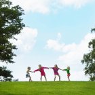 Chicas jugando tira y afloja en el campo contra el cielo azul - foto de stock