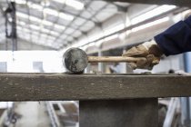 Gros plan de l'ouvrier d'usine avec marteau en caoutchouc dans une usine d'armature en béton — Photo de stock