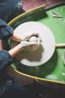 Overhead view of young womans hands shaping clay on pottery wheel — Stock Photo
