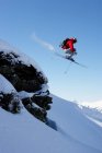 Лыжник прыгает через скалу — стоковое фото