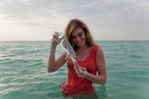 Frau im Meer mit Flaschenpost — Stockfoto