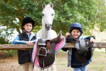 Girls with pony holding saddles — Stock Photo