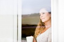 Woman having cup of coffee at window — Stock Photo