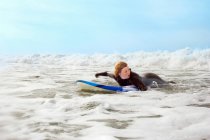 Жінка лежить на дошці для серфінгу, весло — стокове фото