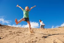 Дві дівчини стрибають на пляжних дюнах — стокове фото