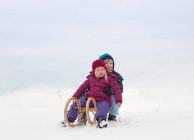 Bambini seduti sulla slitta nella neve — Foto stock