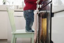 Boy standing on chair in kitchen — Stock Photo