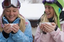 Two females in ski-wear holding cups — Stock Photo
