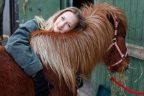 Smiling woman hugging horse outdoors — Stock Photo