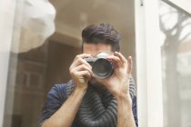 Portrait of young man photographing with SLR camera — Stock Photo