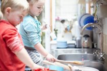 Enfants lavant la vaisselle ensemble — Photo de stock