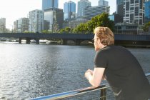 Человек с видом на городскую реку на мосту — стоковое фото