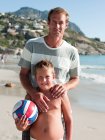 Отец и сын на пляже с мячом — стоковое фото