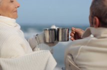 Couple aîné prenant un verre sur la plage — Photo de stock