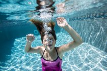 Girl blowing bubbles in swimming pool — Stock Photo
