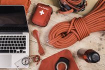 Вид на альпинистское снаряжение с красным набором первой помощи, альпинистские канаты и ноутбук — стоковое фото