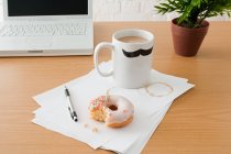 Kaffee und Donut auf dem Schreibtisch — Stockfoto