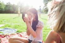 Female friends applying make up at park party — Stock Photo