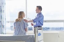Doctor talking to patient sitting on hospital bed — Stock Photo