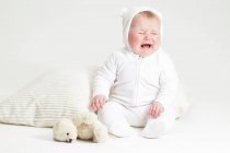 Portrait of crying baby girl and teddy bear — Stock Photo