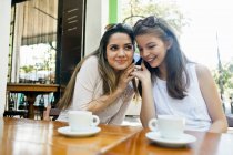 Female friends listening to cellphone together — Stock Photo