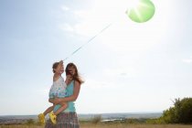 Madre e hija llevando globo - foto de stock