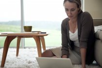 Жінка сидить на підлозі за допомогою ноутбука — стокове фото