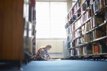 Jovem estudante universitário do sexo feminino trabalhando no chão da biblioteca — Fotografia de Stock