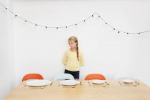 Дівчина чекає за столом з порожніми тарілками — стокове фото